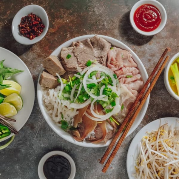 Overhead view of a bowl of Pho Ngon pho with various meats, noodles, and garnishes.