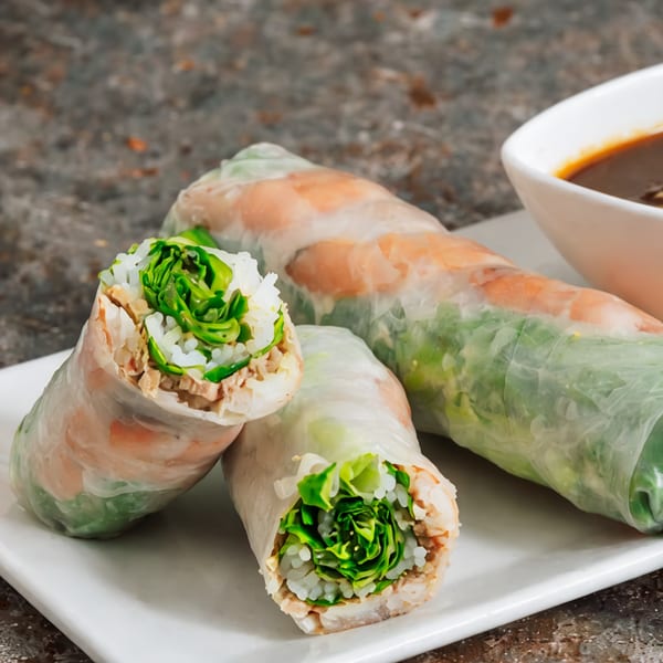 Fresh Vietnamese spring rolls with shrimp, pork, rice noodles, and lettuce, served with dipping sauce.